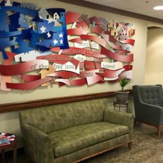 A waiting room featuring a mural with an American flag design and a green sofa.