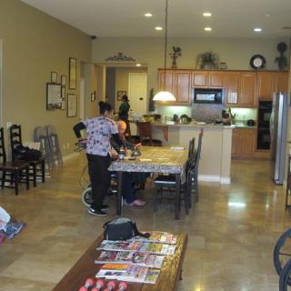 A modern kitchen and dining area with people preparing food.