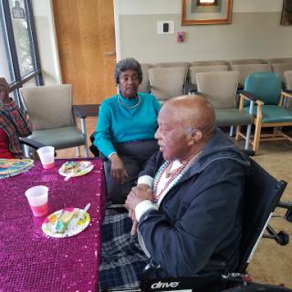 A warm community gathering for seniors, featuring food and cheerful conversations.