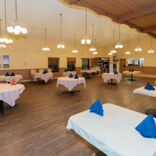 A spacious and elegantly decorated restaurant dining room with neatly arranged tables and chandeliers.