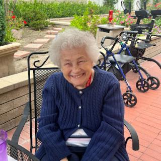 A joyful elderly woman enjoying a sunny day in the garden.