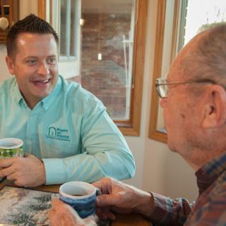 Two men engaged in a friendly conversation over coffee in a cozy indoor setting.