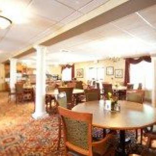 A cozy dining room with neatly arranged tables and chairs, featuring warm lighting and decorative elements.