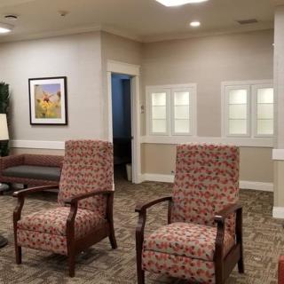 A cozy waiting room with patterned armchairs and framed wall art.