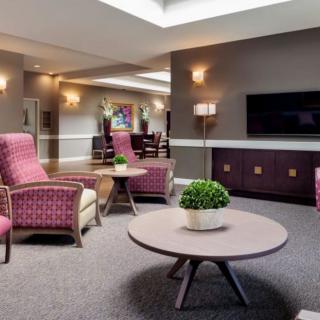 A cozy lounge area featuring comfortable seating, a coffee table with a plant, and a television on the wall.