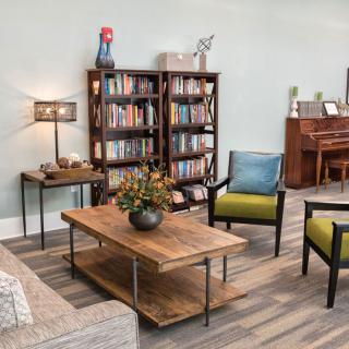 Cozy living room with a bookshelf, comfortable seating, and a piano.