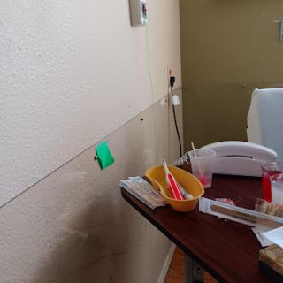 A view of a workspace featuring a table with various stationery items, a telephone, and a wall with visible electrical outlets.