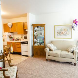 A cozy living area with a sofa, decorative cabinet, and a view into the adjacent kitchen space.