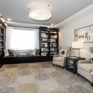 A cozy, modern living room with bookshelves, a window seat, and comfortable armchairs.