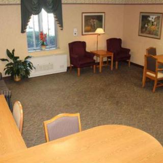 A cozy waiting room with chairs, a table, a lamp, and wall decorations.