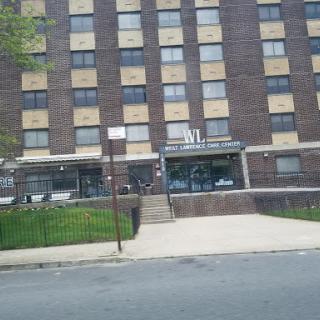 An apartment building featuring a brick facade with boarded windows.