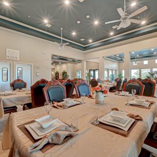 A beautifully set dining room with elegant table settings and chandeliers, ready for guests.