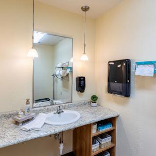 A modern bathroom featuring a sleek sink, stylish lighting, and organized storage.