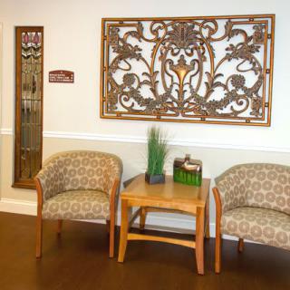 A cozy waiting area with two upholstered chairs, a small wooden table, and decorative wall art.