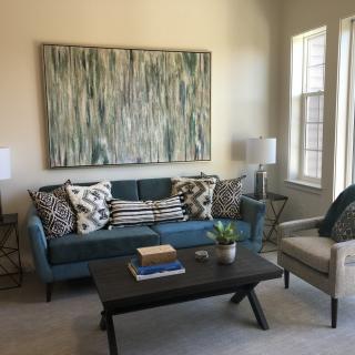 A cozy living room featuring a modern sofa with decorative pillows, a large abstract painting on the wall, and a stylish coffee table.