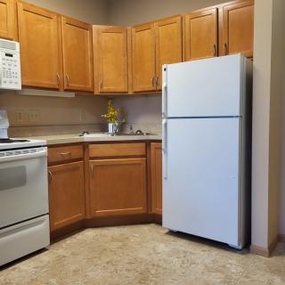 A modern kitchen with wooden cabinets, a refrigerator, oven, microwave, and sink.
