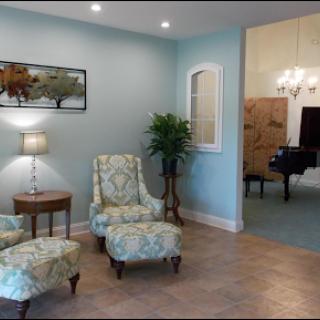 A cozy living room featuring elegant armchairs, a piano in the background, and tasteful decor.