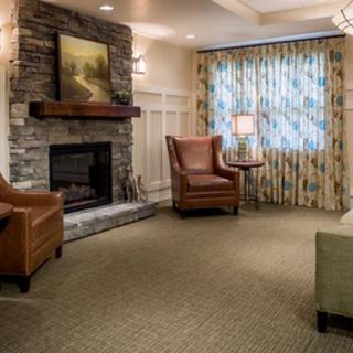A cozy living room featuring a stone fireplace, comfortable armchairs, and soft lighting.