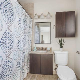 A modern bathroom with a patterned shower curtain and sleek wooden cabinetry.