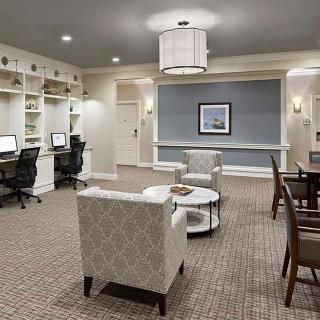 A modern office space featuring multiple workstations with computers, comfortable seating, and elegant lighting.