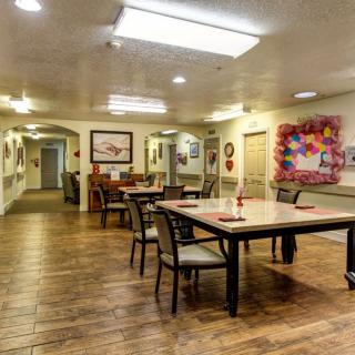 An interior view of a dining area with tables and chairs, featuring artwork on the walls.