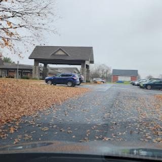 A view of a parking area surrounded by fallen leaves under a cloudy sky.