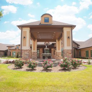 A beautiful residential building with a garden and fountain in the foreground.