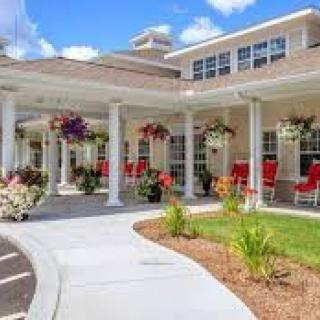 A charming building with a spacious porch adorned with flowers and outdoor seating.