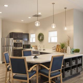 A modern kitchen with a dining area featuring pendant lighting and stainless steel appliances.