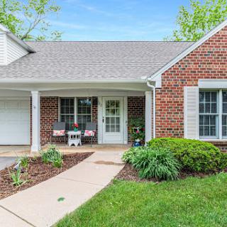 A charming brick house with a welcoming front porch and well-maintained landscaping.