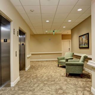 A well-lit hallway with elevators and a comfortable seating area.