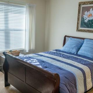 A cozy bedroom with a neatly made bed and natural light coming through the window.
