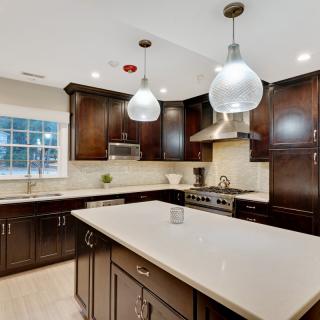 A modern kitchen with dark wood cabinets, an island countertop, and stainless steel appliances.