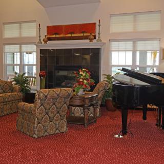 A cozy living room with a grand piano, fireplace, and comfortable seating area.