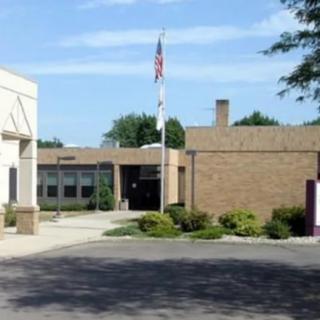 A school building with an American flag outside on a sunny day.