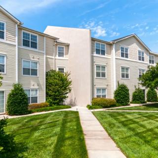A well-maintained suburban apartment complex with manicured lawns and clear blue skies.