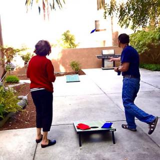 Two people playing a game of cornhole in the backyard.