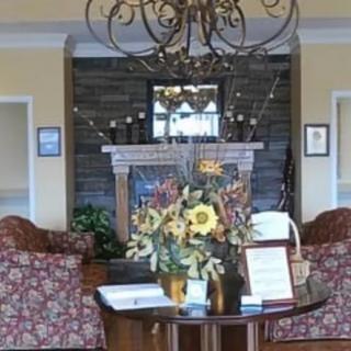A cozy lobby area with elegant decor, featuring a chandelier, floral arrangement, and a fireplace.