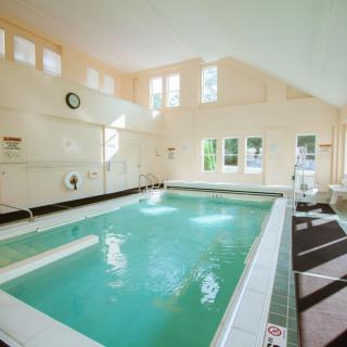 A serene indoor swimming pool area with natural light streaming through the windows.
