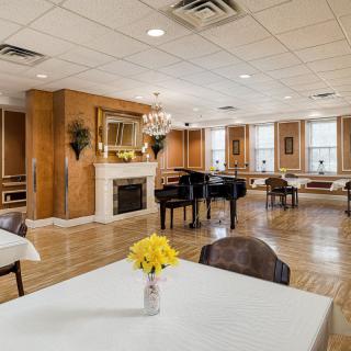 A spacious and elegant room featuring a grand piano, fireplace, and chandelier.