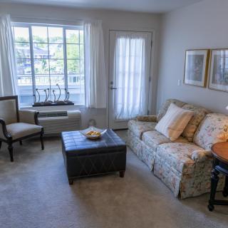 A cozy living room with a sofa, chairs, and a coffee table by the window.