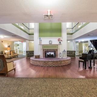 A spacious lobby area featuring a central fireplace, a grand piano, and comfortable seating arrangements.