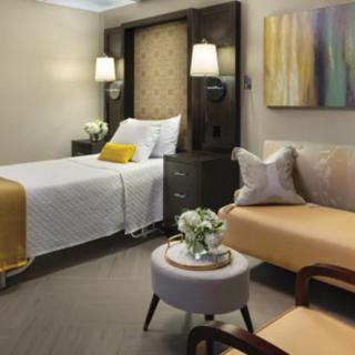 A modern bedroom with contemporary decor, featuring a bed, sofa, and stylish lighting.