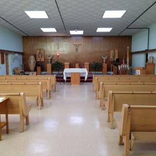 Interior view of a church featuring wooden pews and an altar with a crucifix.