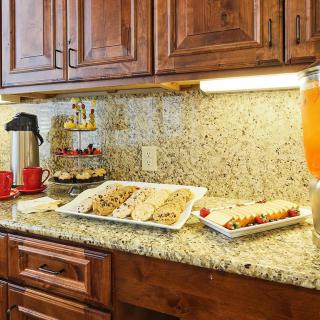 A kitchen countertop with snacks, a coffee pot, and refreshments.
