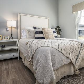 A cozy and well-decorated bedroom with a neatly made bed, stylish pillows, and a lamp on the nightstand.