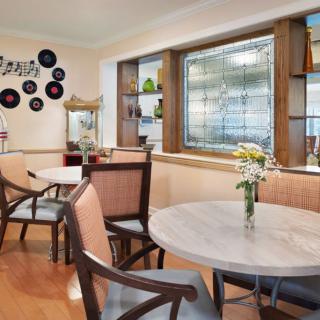 A cozy cafe interior with tables and chairs, decorated with plants and wall art.