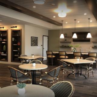 A modern cafe interior with round tables, chairs, and a bar area.
