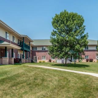 A residential apartment complex with a central courtyard featuring a tree and well-maintained grass.