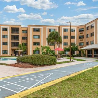 An exterior view of a multi-story hotel with palm trees and well-maintained landscaping.